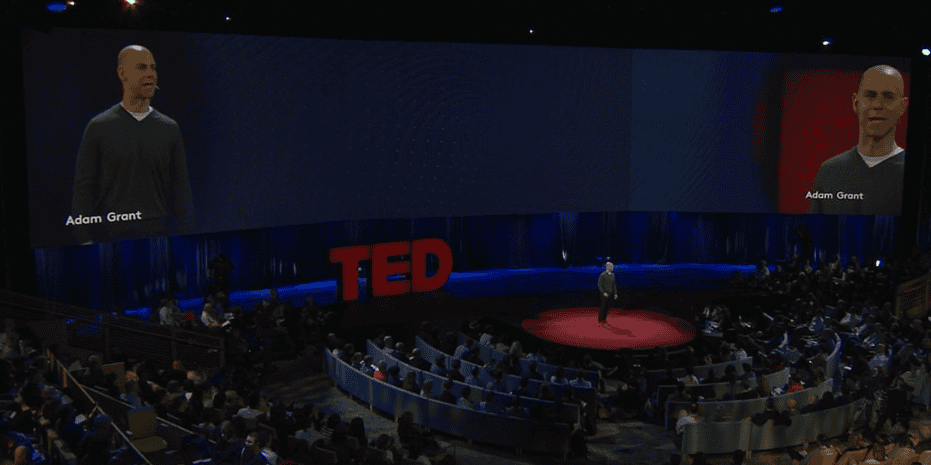 Adam Grant standing on the circular red stage at a main TED conference, presenting his talk on the surprising habits of original thinkers.