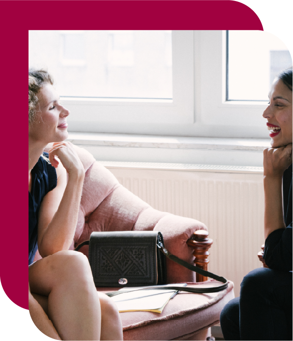 Two women in a meeting discussing progress in a relaxed, professional setting. Text: Progress becomes visible and measurable.
