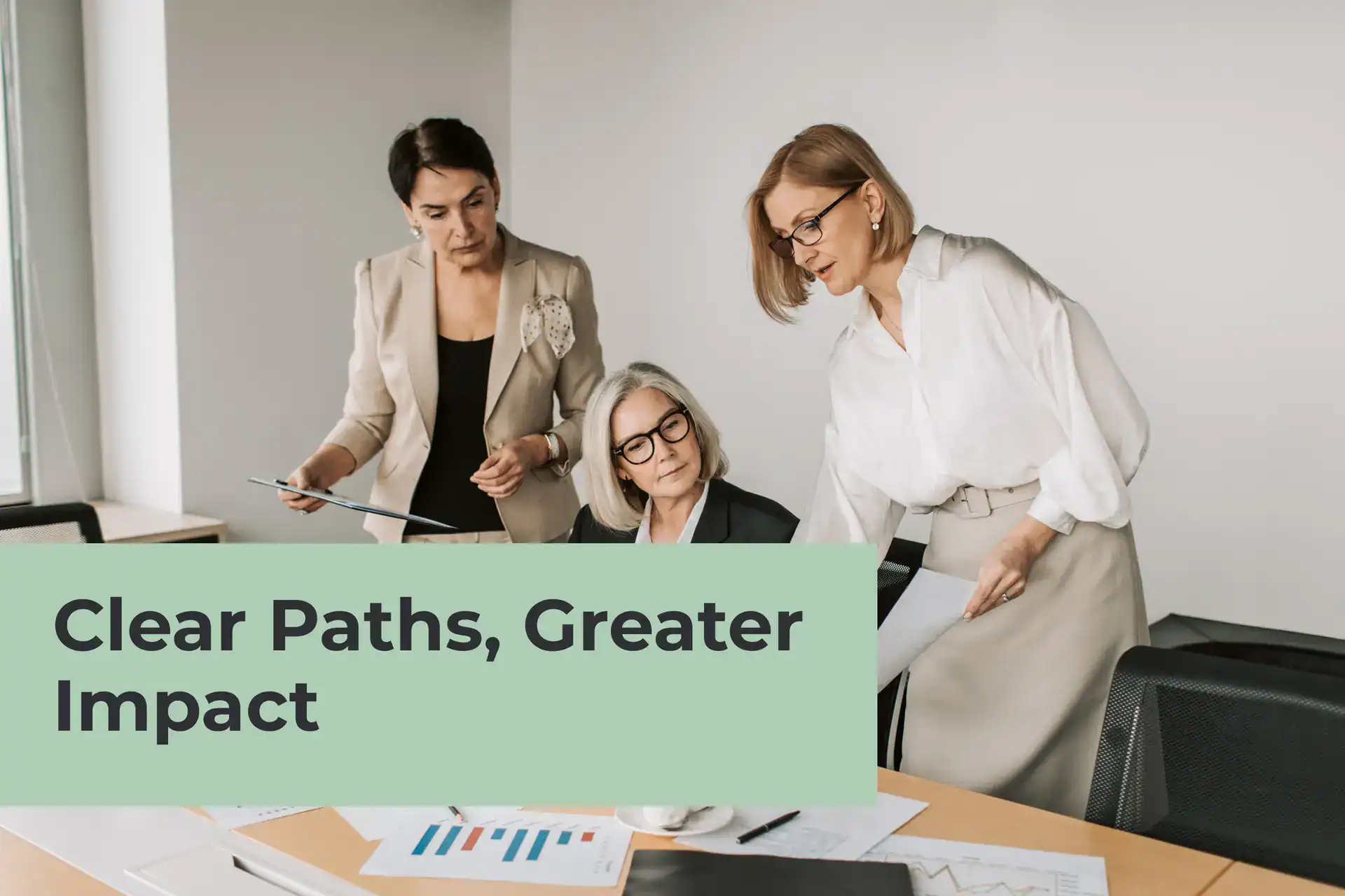 Three professional women in corporate attire collaborating around an office table covered in charts and documents. A light green graphic overlay on the left features the bold text: "Clear Paths, Greater Impact."