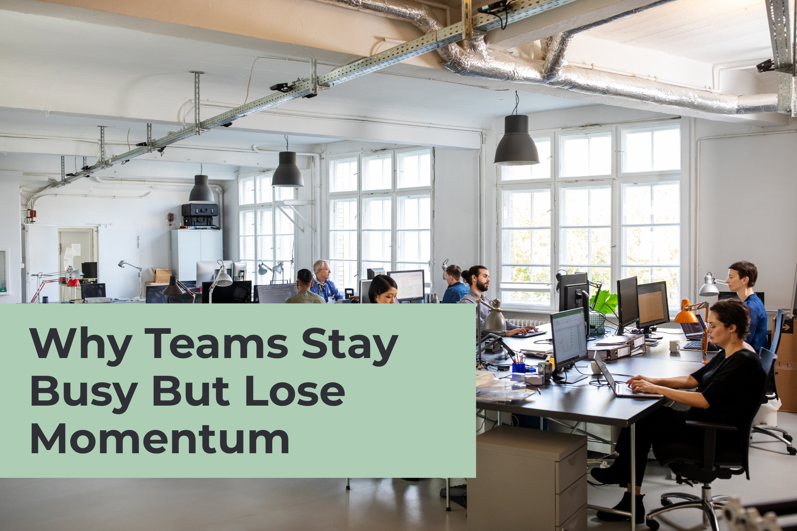 An open-plan office space filled with employees working at rows of desks with computers. A large green block in the foreground features the text, "Why Teams Stay Busy But Lose Momentum."